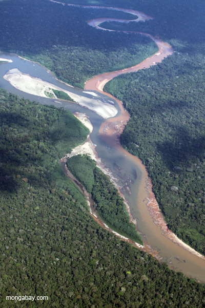 Muddy toxin-laden river that drains the Río Huaypetue gold mine joining a clearwater river in the Peruvian Amazon.