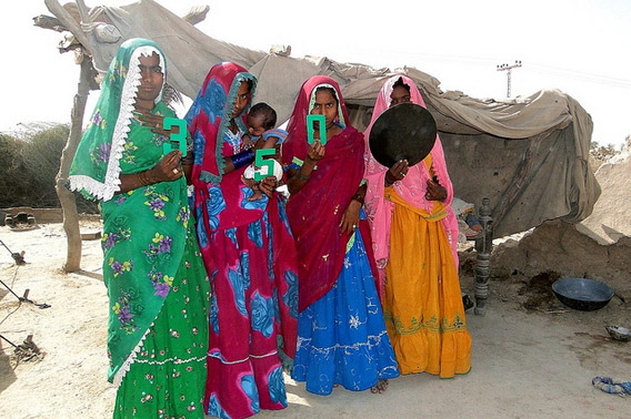 Women hold a dot outside of the temporary structure that they have been living in since the devastating 2010 floods destroyed their home. Photo courtesy of: 350.org.