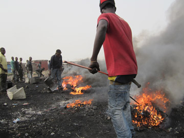 A young man stokes burning e-waste. Photo by: David Fedele.