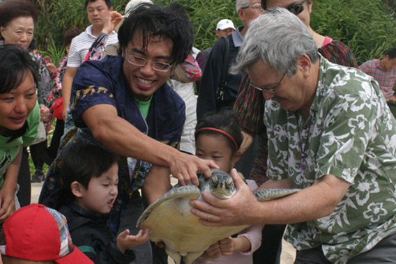 放生前Frederick Yeh（左）、George Balazs(右)和孩子们一起观赏海龟Crush。照片来自911国际海龟保护组织