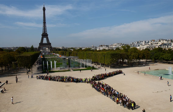  People create the image of a turbine backed by the Eifel Tower in Paris. Photo by: Nicolas Chauveau.